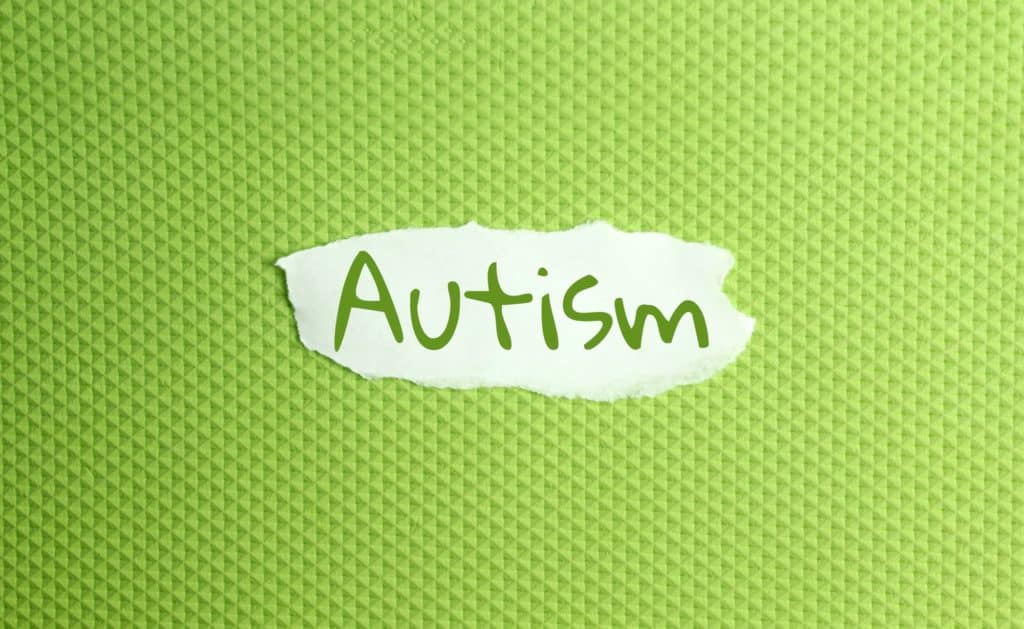 un papel rasgado con una inscripción autista sobre fondo verde