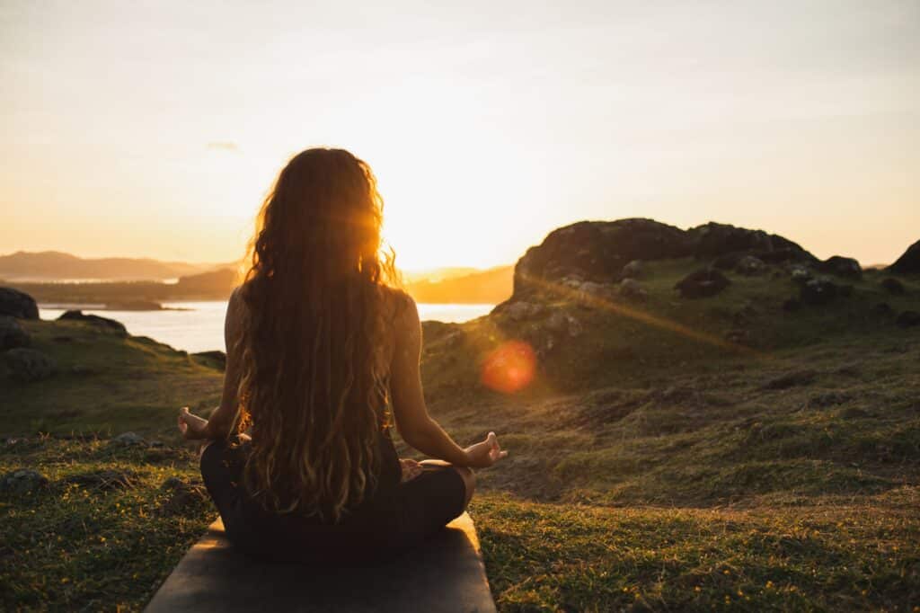Mujer meditando yoga sola en las montañas al amanecer. Vista desde atrás. Estilo de vida de los viajes Espíritu