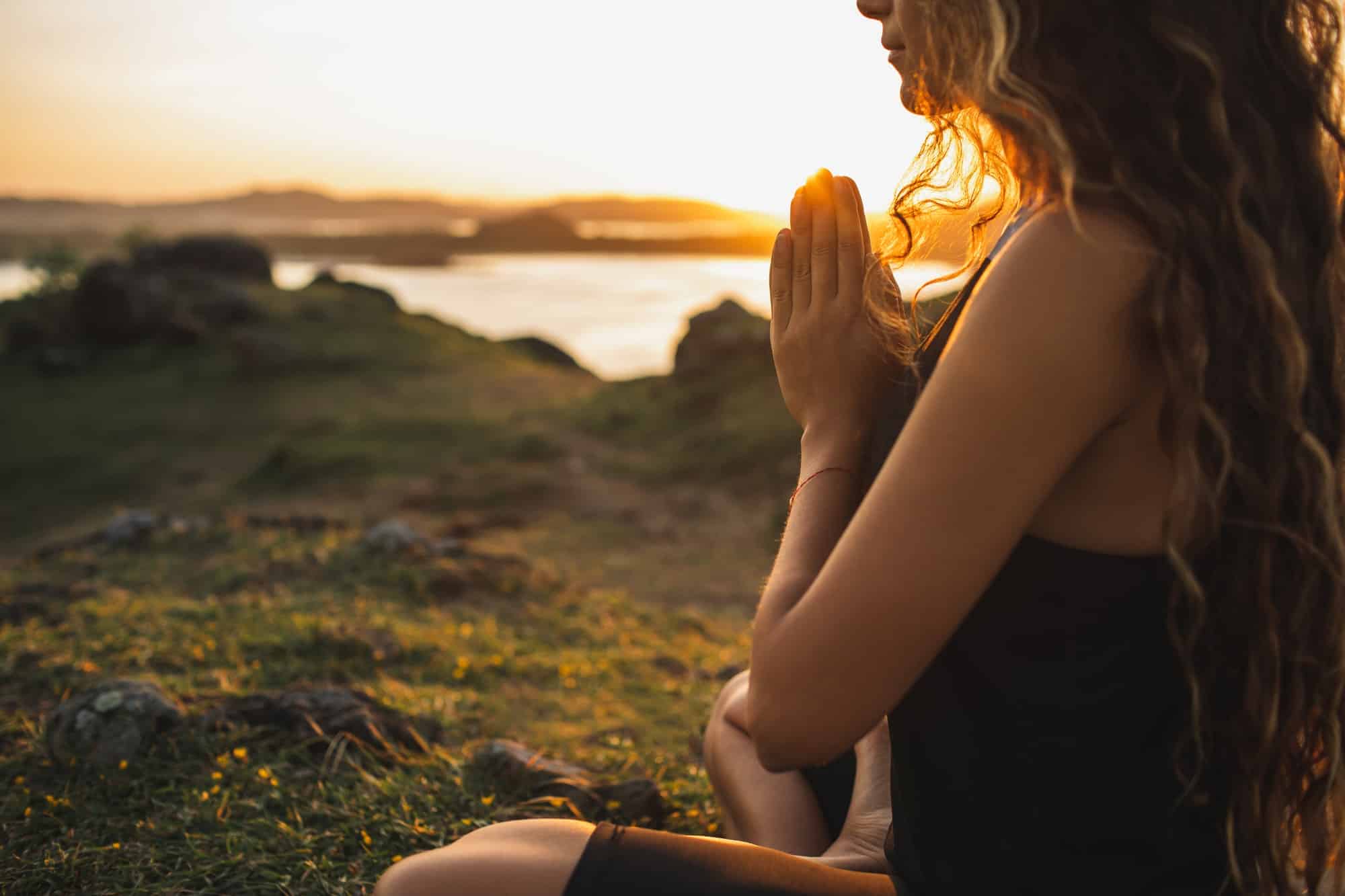 Mujer rezando sola al amanecer. Fondo de la naturaleza. Concepto espiritual y emocional