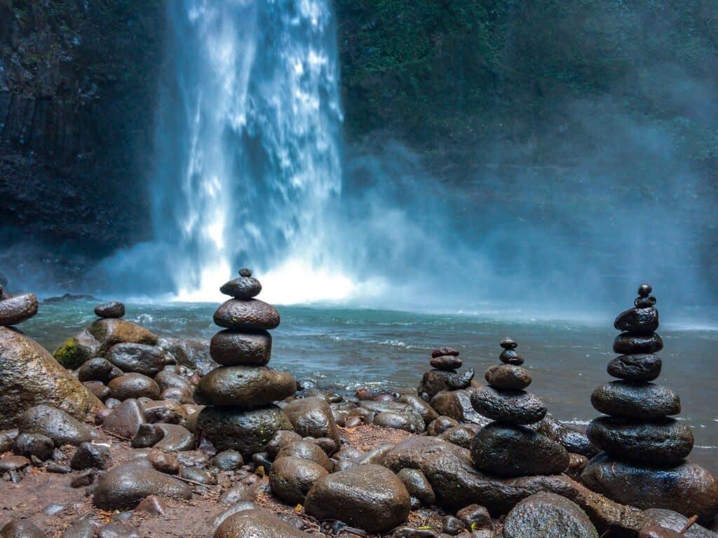 Piedras apiladas para la meditación frente a una cascada azul en la selva