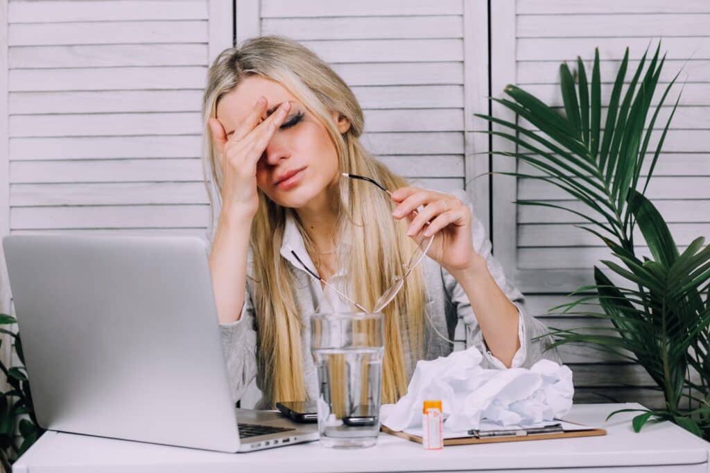 Una mujer de negocios estresada que trabaja desde casa con su portátil y tiene dolor de cabeza